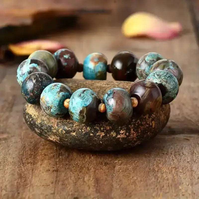 Mala bracelet with earth-toned beads resting on a stone